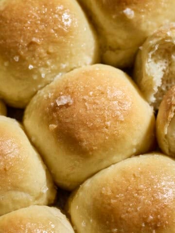 Sourdough Discard Potato Dinner Rolls topped with melted butter and flaky sea salt.