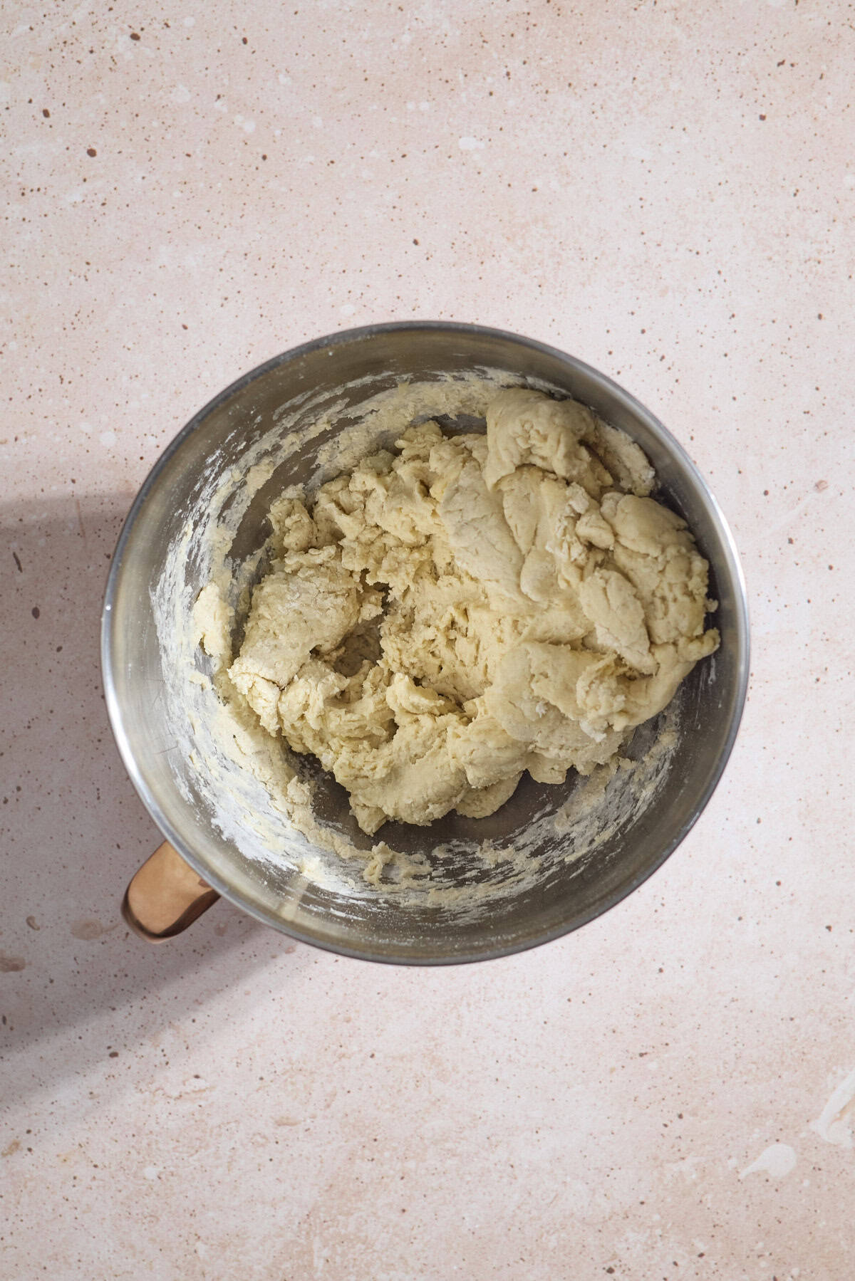 Shaggy dough in the bowl of a stand mixer.