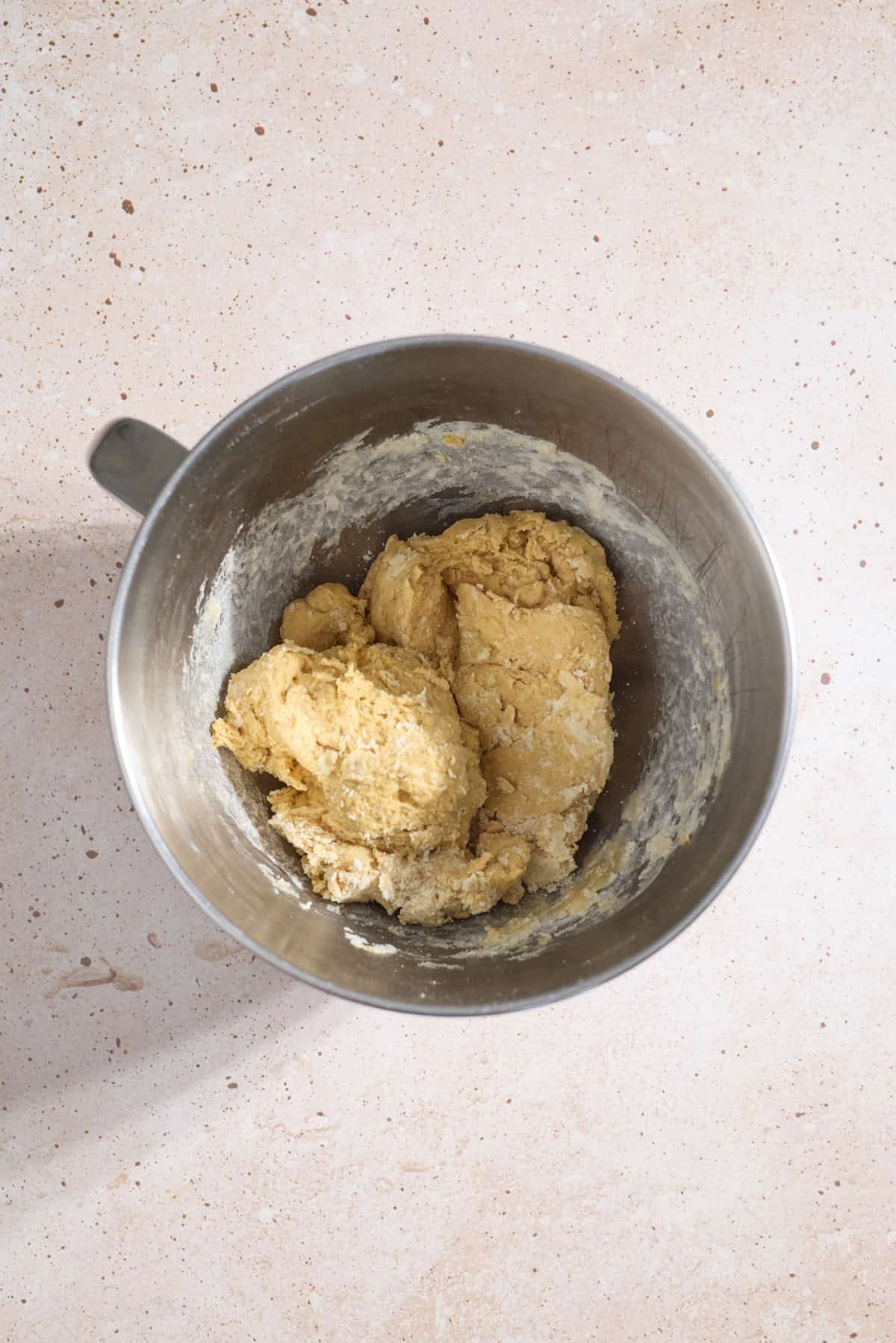 Shaggy dough mixture in the bowl of a stand mixer.