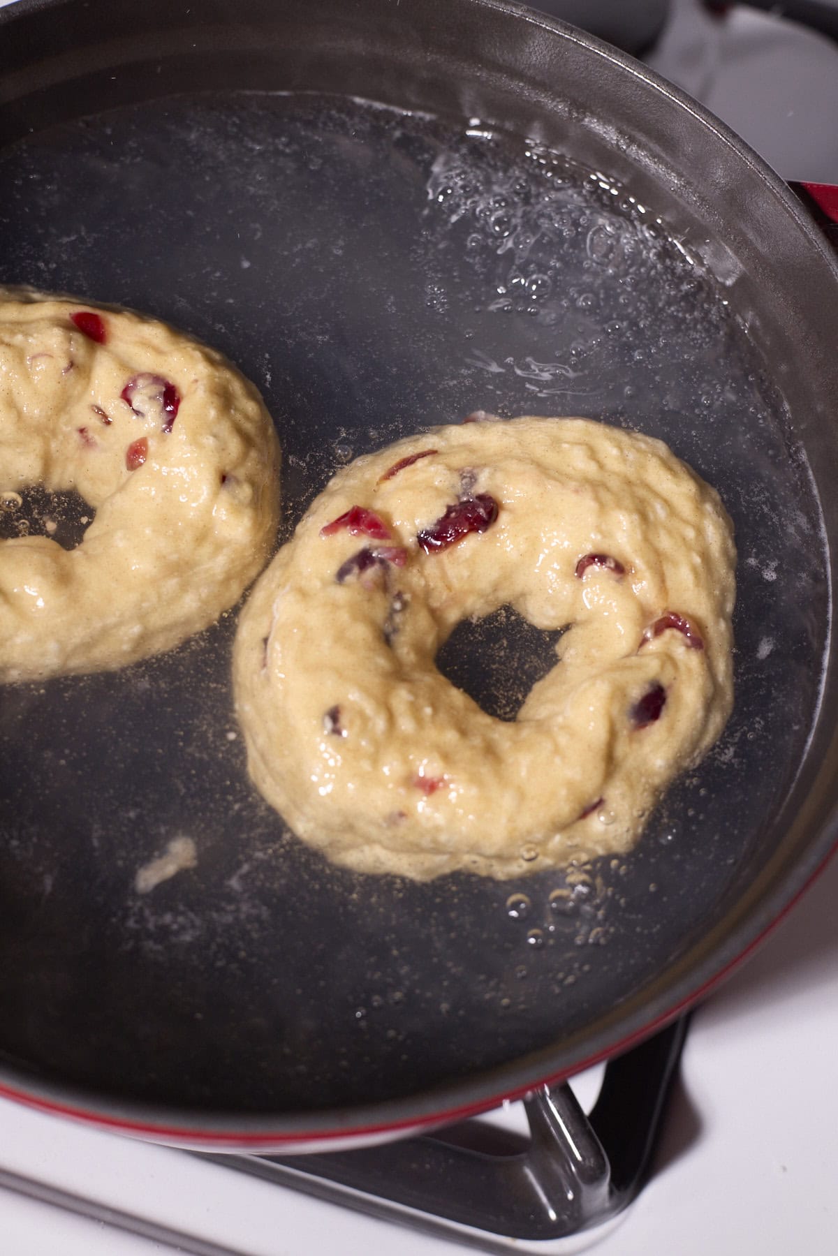 Bagels floating in a boiling pot of water.