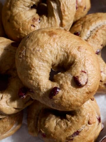 A pile of Sourdough Discard Cranberry Bagels on a wooden tray.