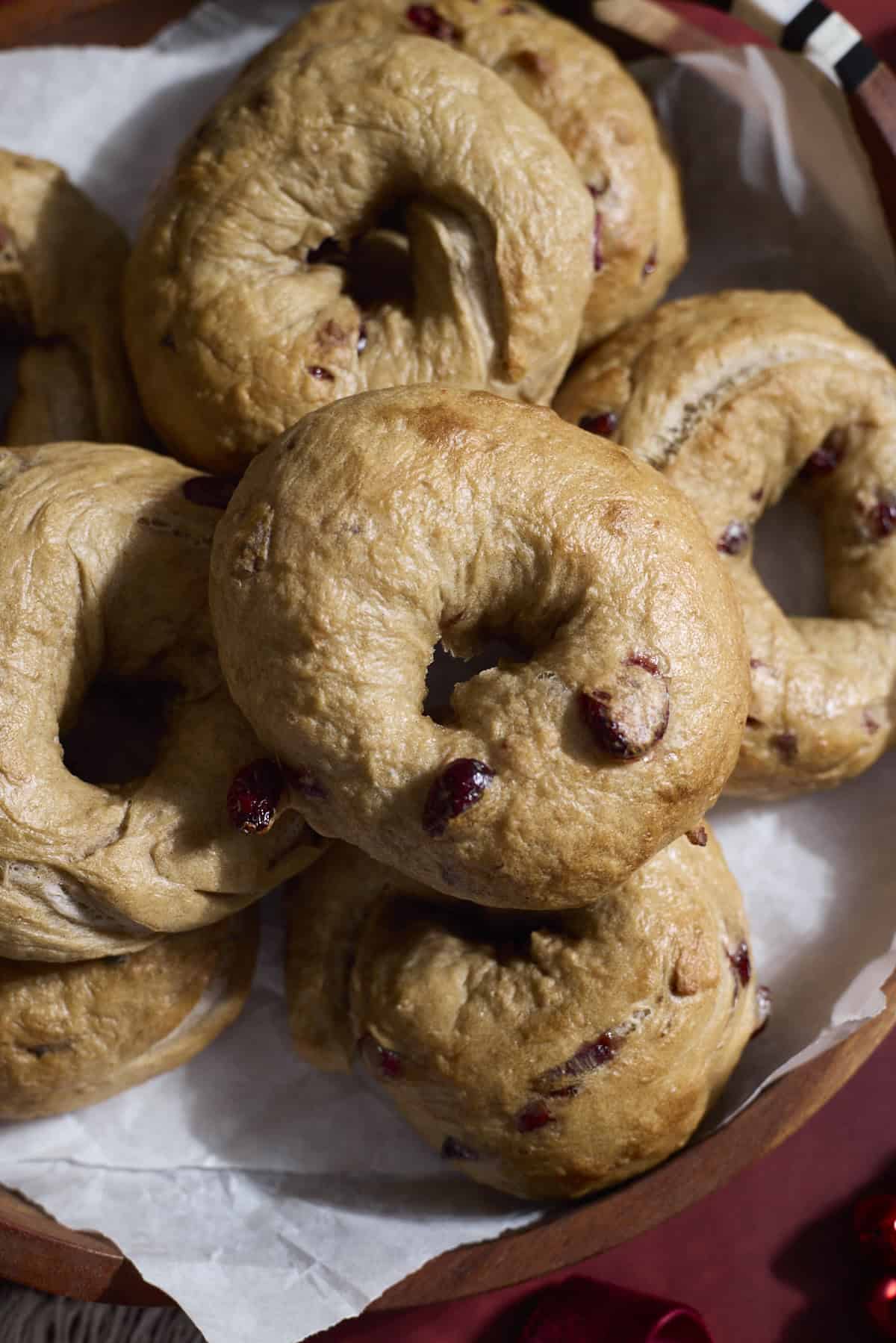 A pile of Sourdough Discard Cranberry Bagels on a wooden tray.