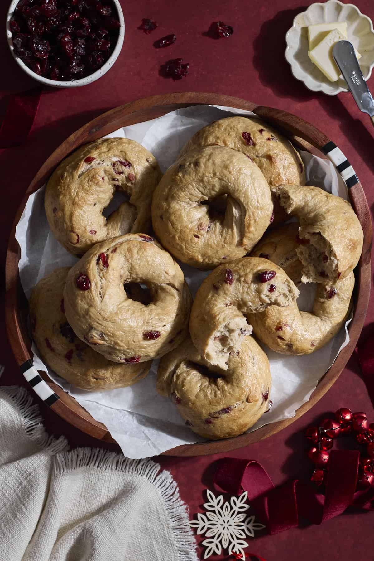A pile of Sourdough Discard Cranberry Bagels on a wooden tray.