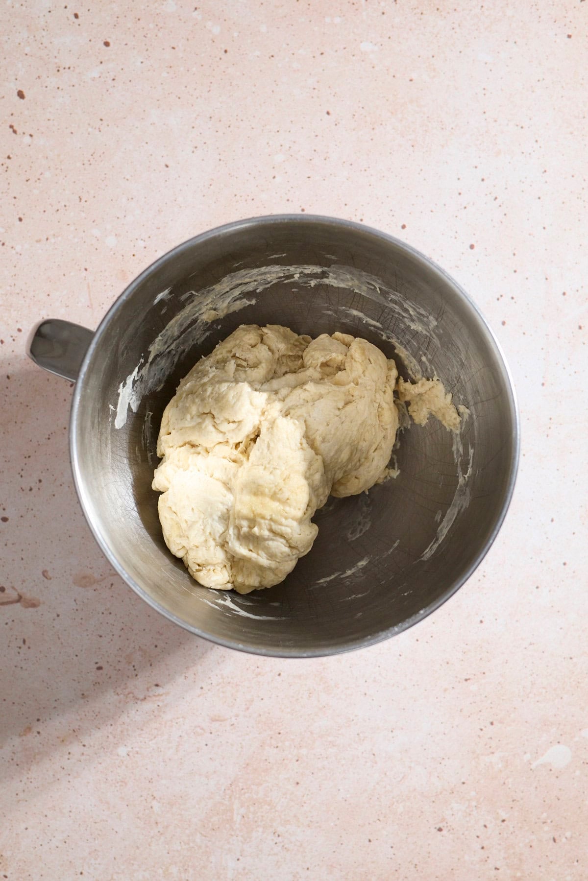 Shaggy dough in the bowl of a stand mixer.