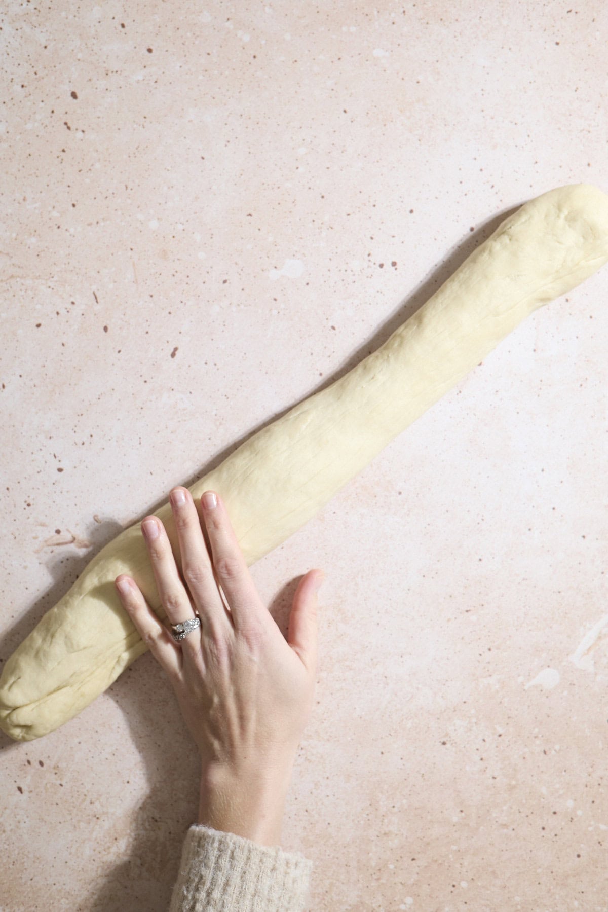 Dough being rolled into a long log.