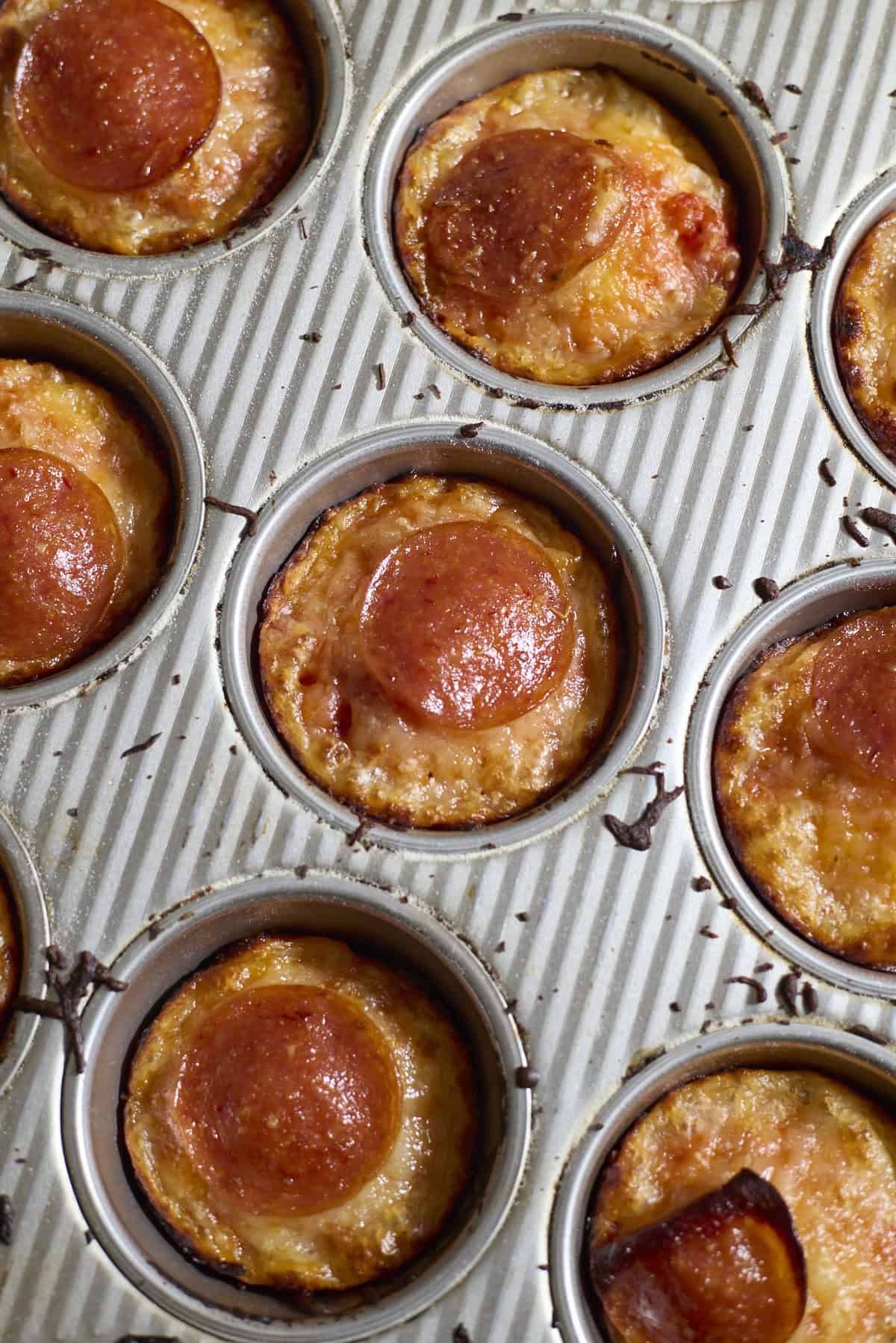 Miniature pizzas in the muffin pan after baking.