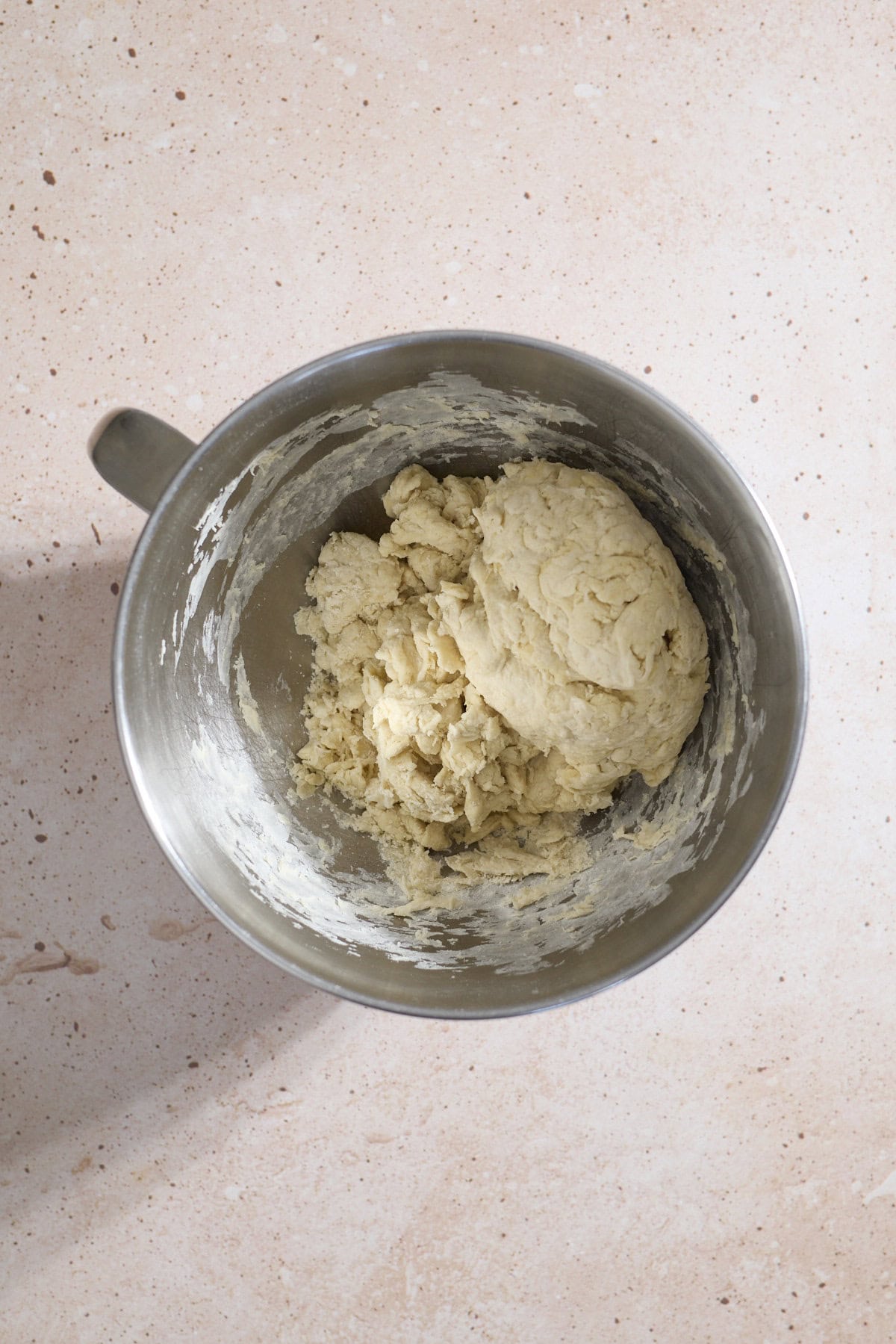 Dough being mixd in the bowl of a stand mixer.