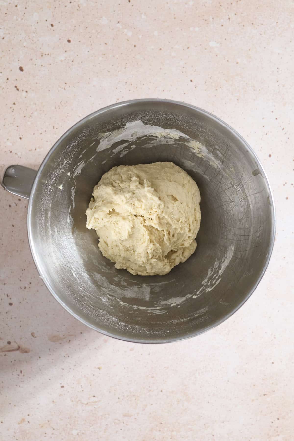 Shaggy dough in the bowl of a stand mixer.