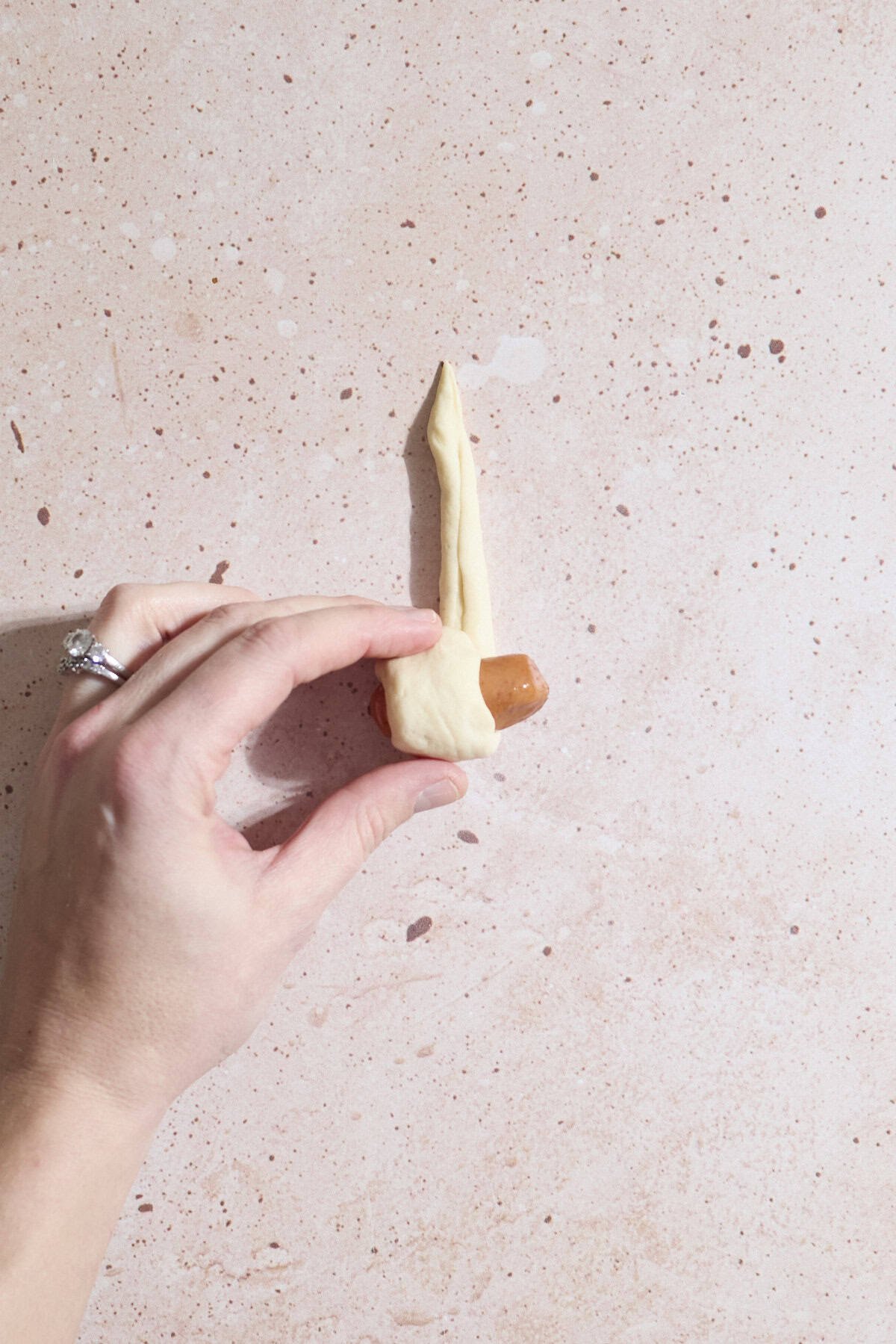 Cocktail sausage being wrapped in the dough.