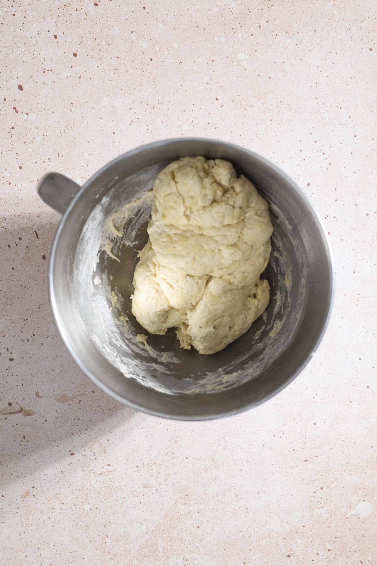 Shaggy dough in the bowl of a stand mixer.