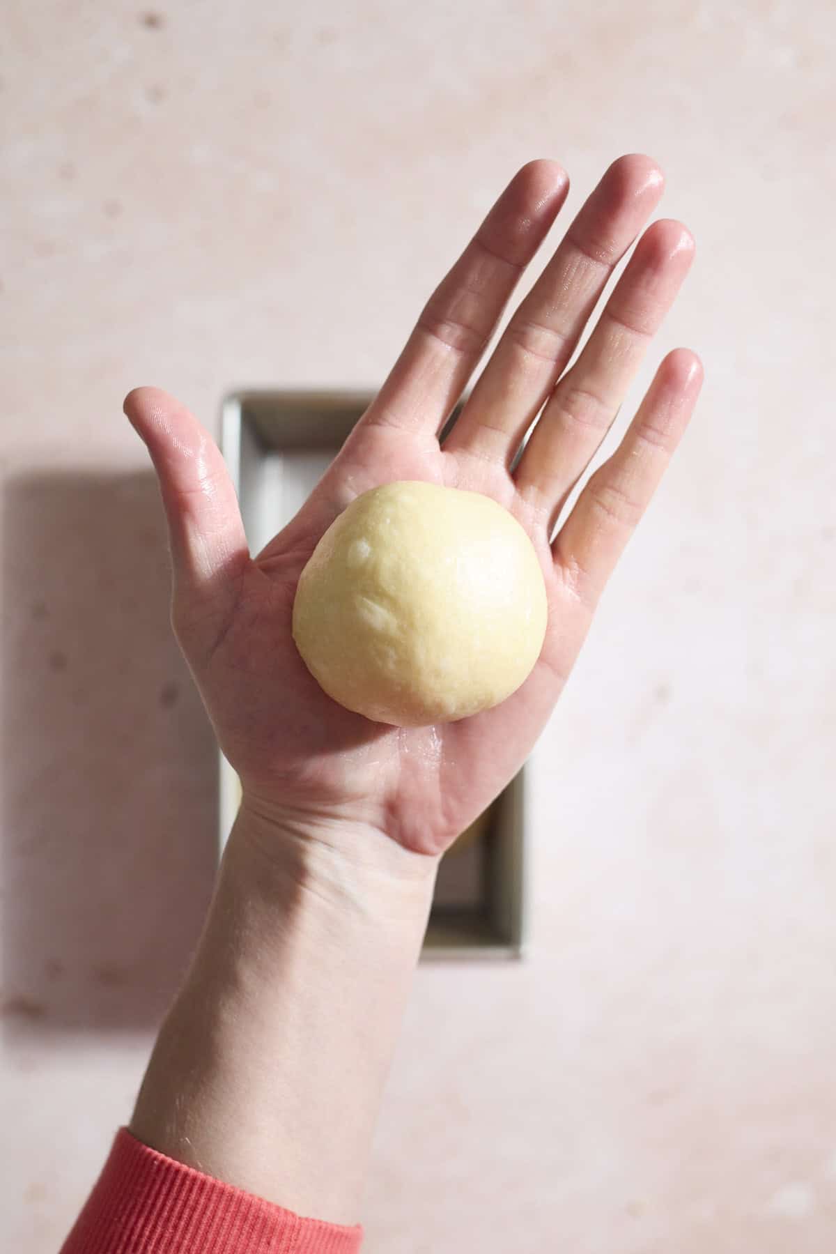 Dough rolled into a ball in the palm of a hand.