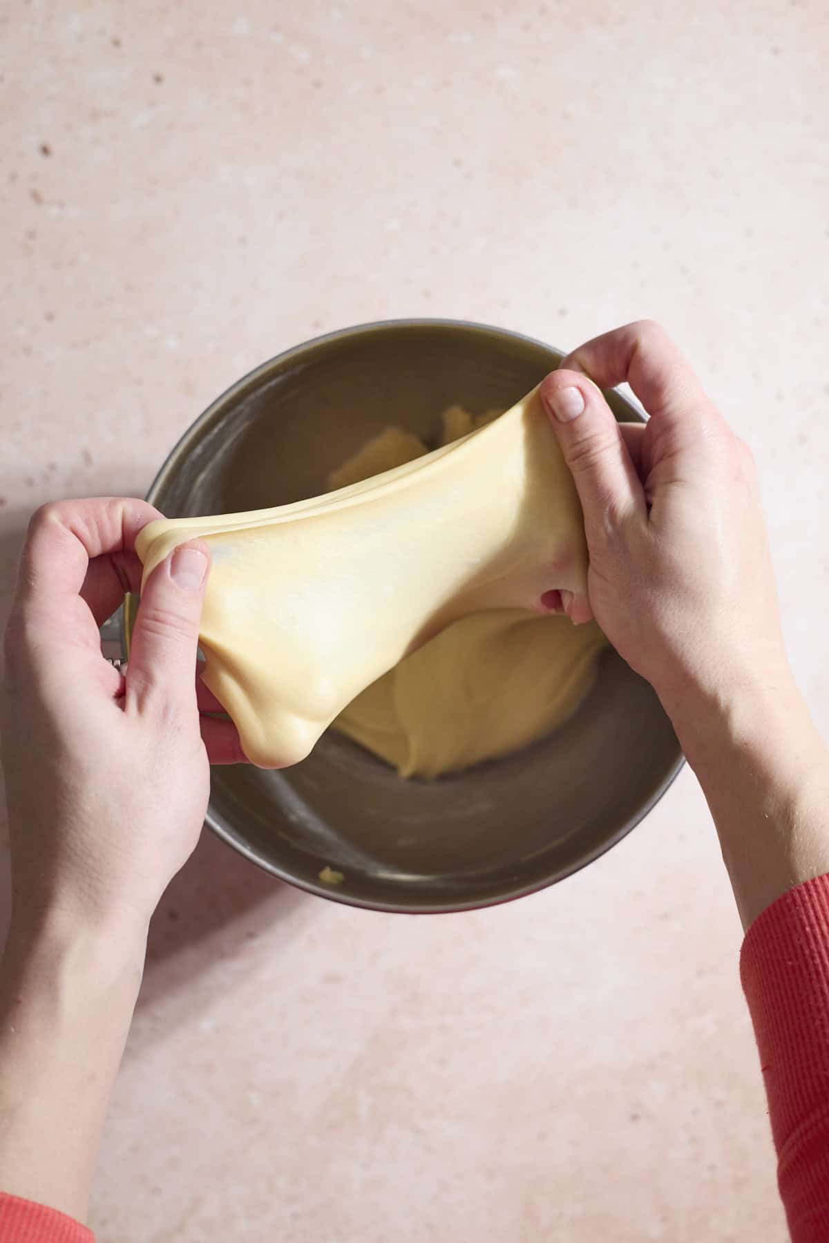 Dough being stretched between two hands.