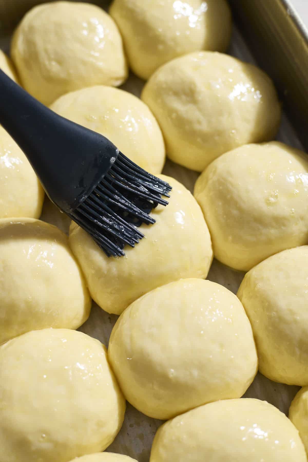 Brushing egg wash on rolls.