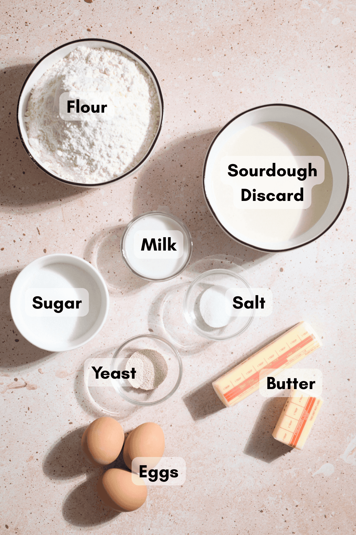 Ingredients for Sourdough Discard Brioche Rolls in small bowls.