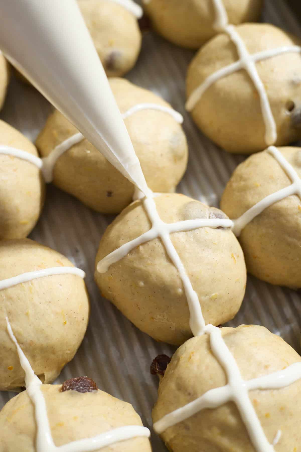 Crosses being piped onto the buns.