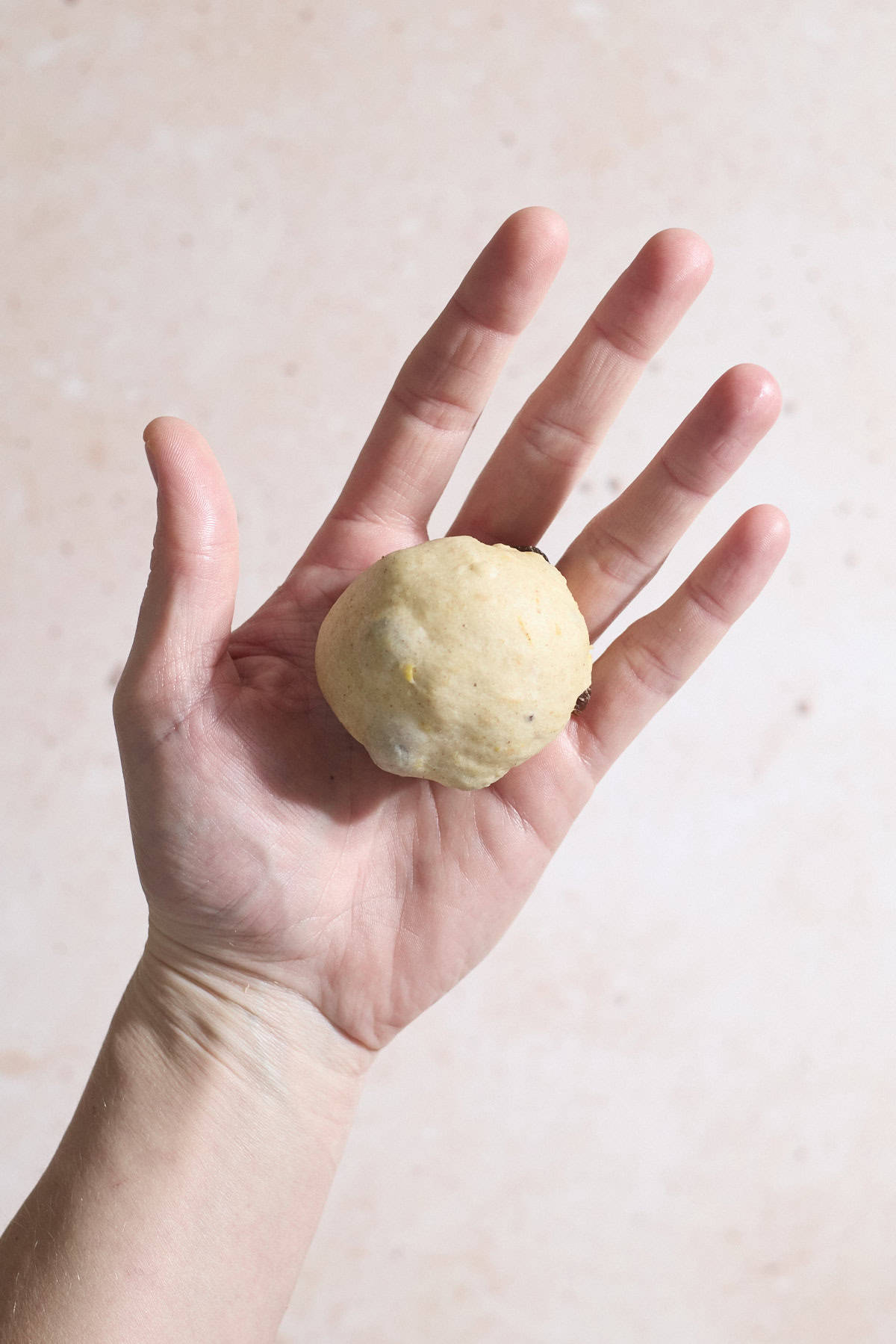 A ball of dough in the palm of a hand.