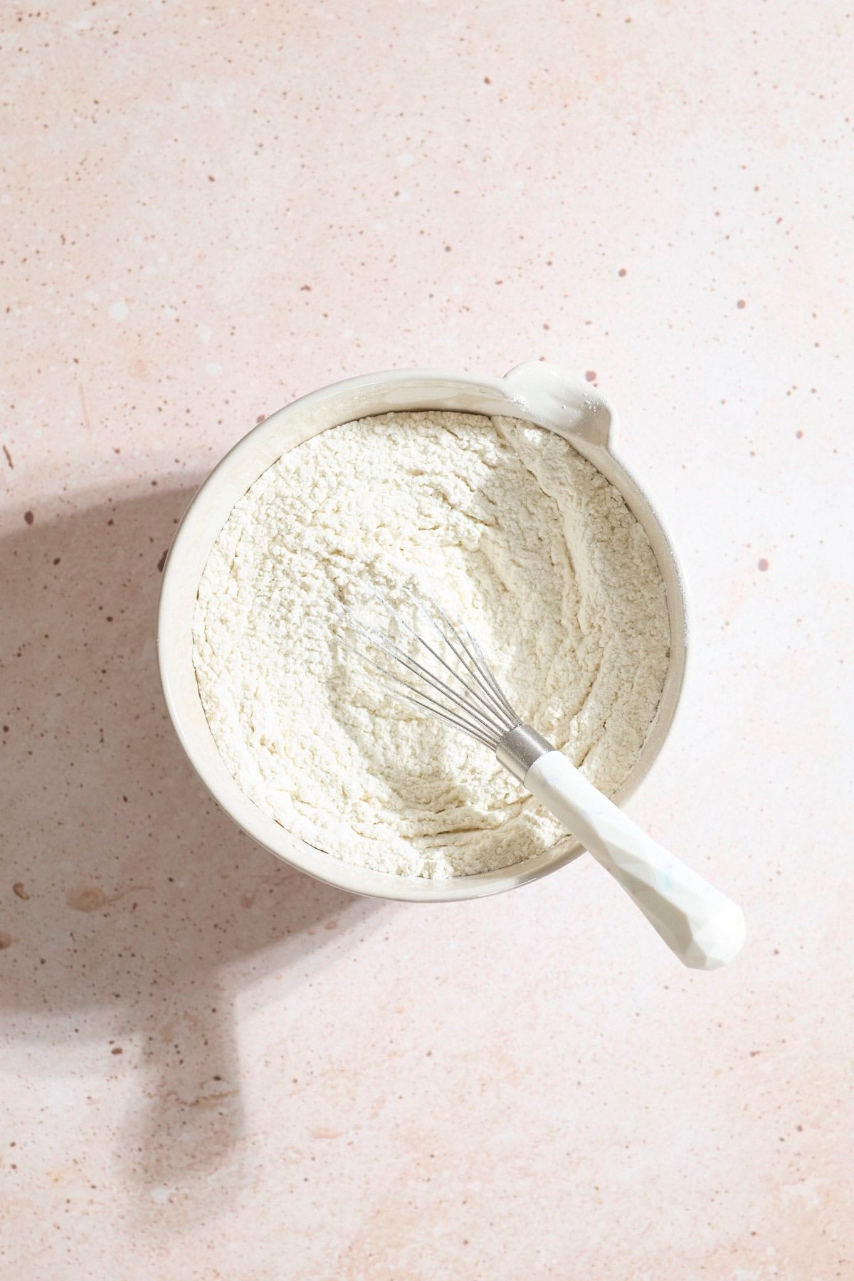Dry ingredients in a mixing bowl with a whisk.