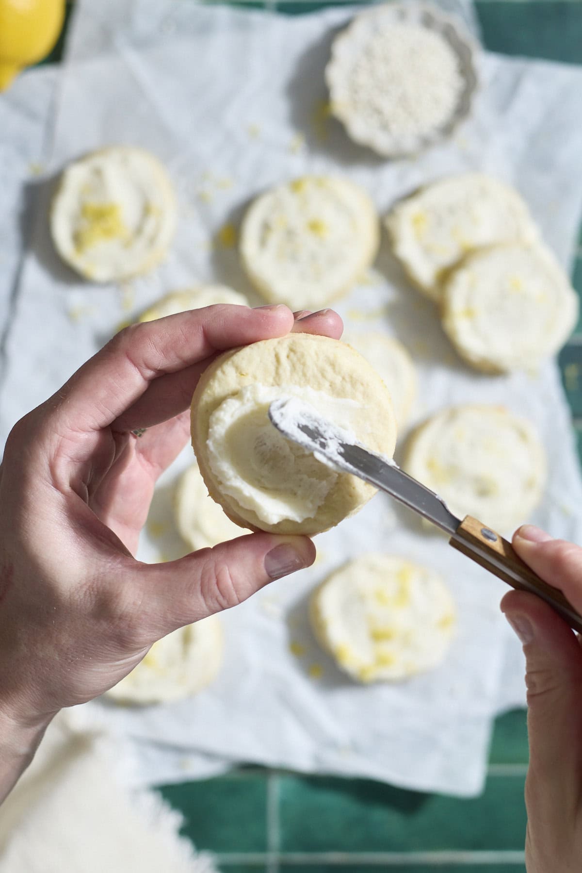 A hand spreading a cookie with frosting.
