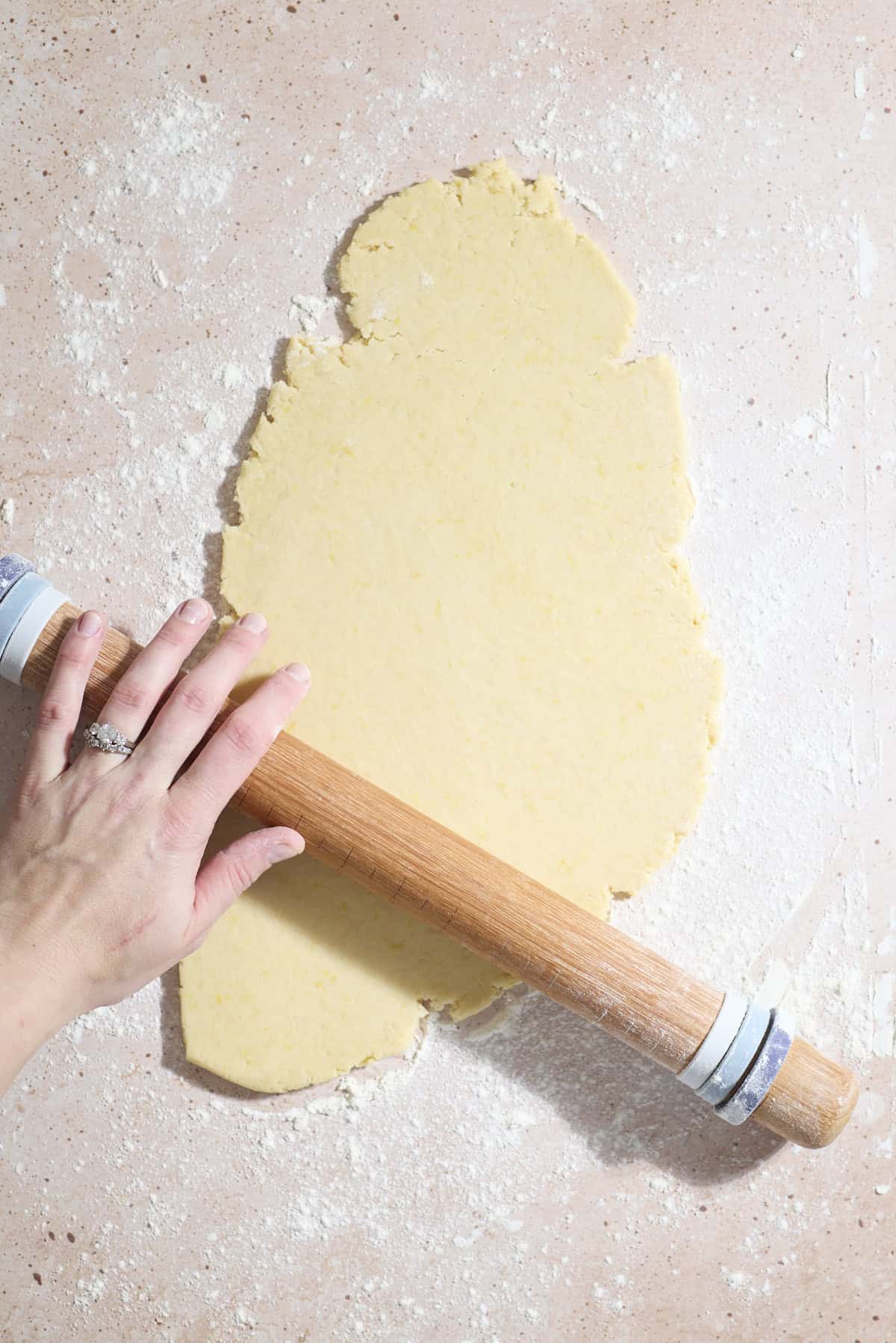 A hand rolling the dough with a rolling pin.