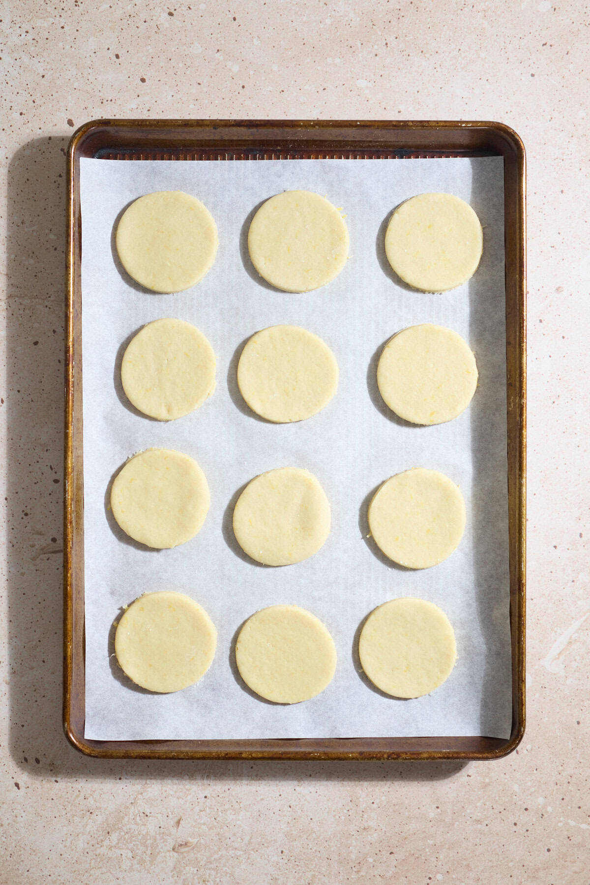 Cookies cut into circles and placed on a baking sheet.