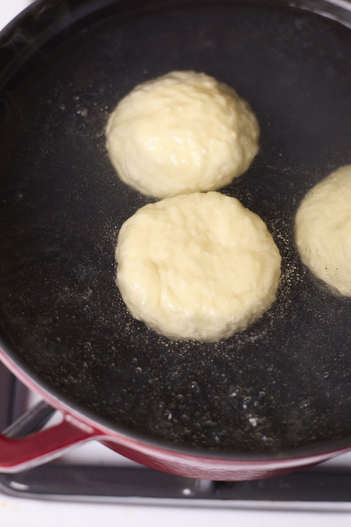 Bagels floating in a pot of boiling water.