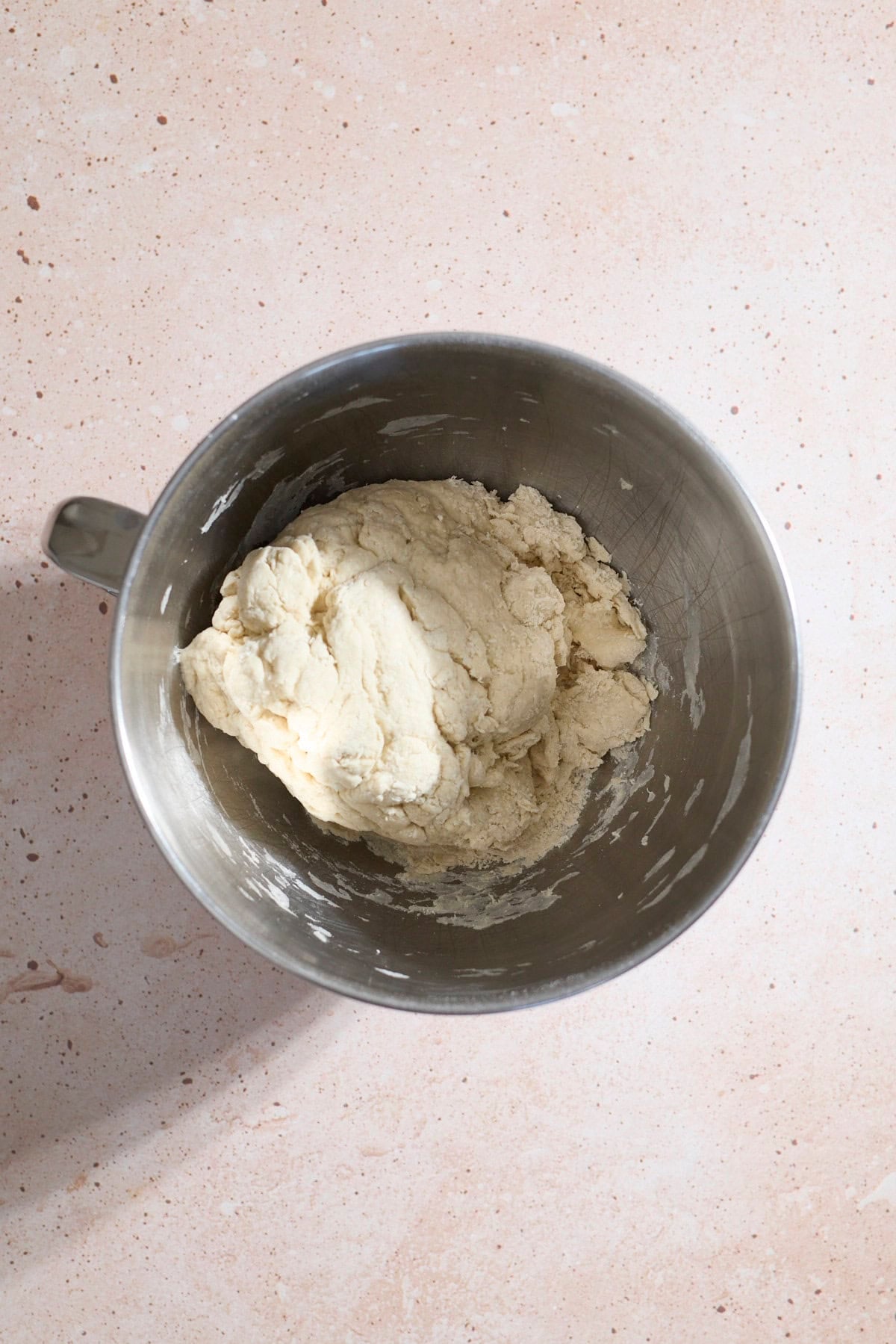 Shaggy dough in the bowl of a stand mixer.