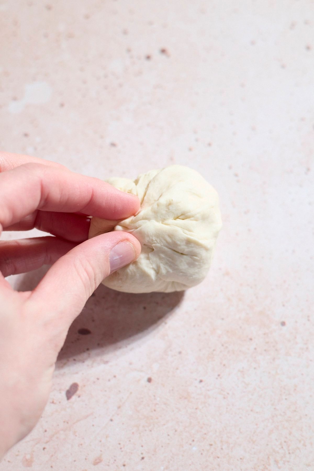 A hand pinching the seams of the dough together.