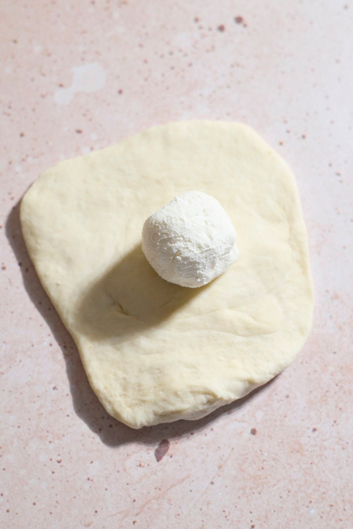 A ball of cream cheese placed in the ceter of the dough.