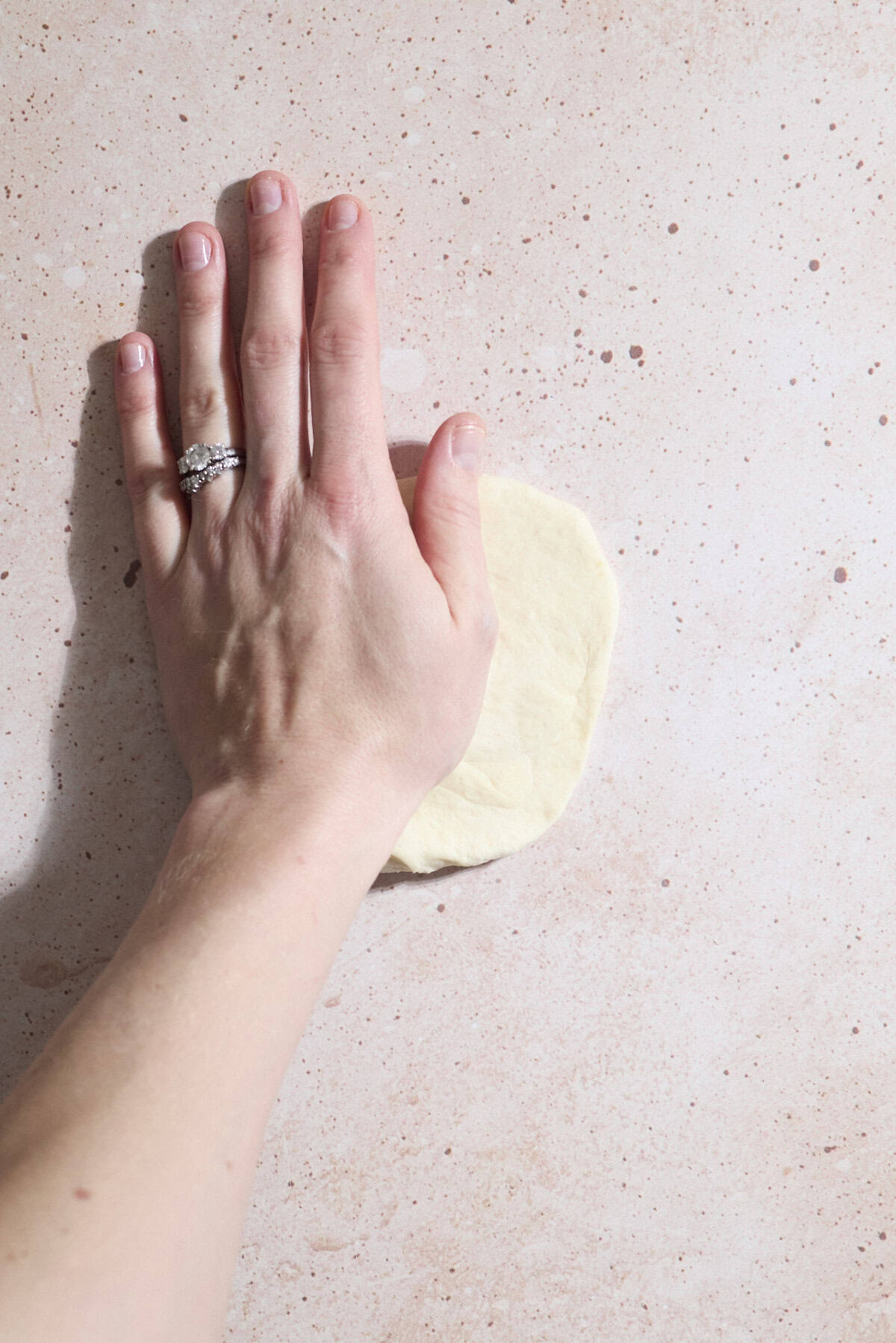 A hand pressing the dough into a circle.