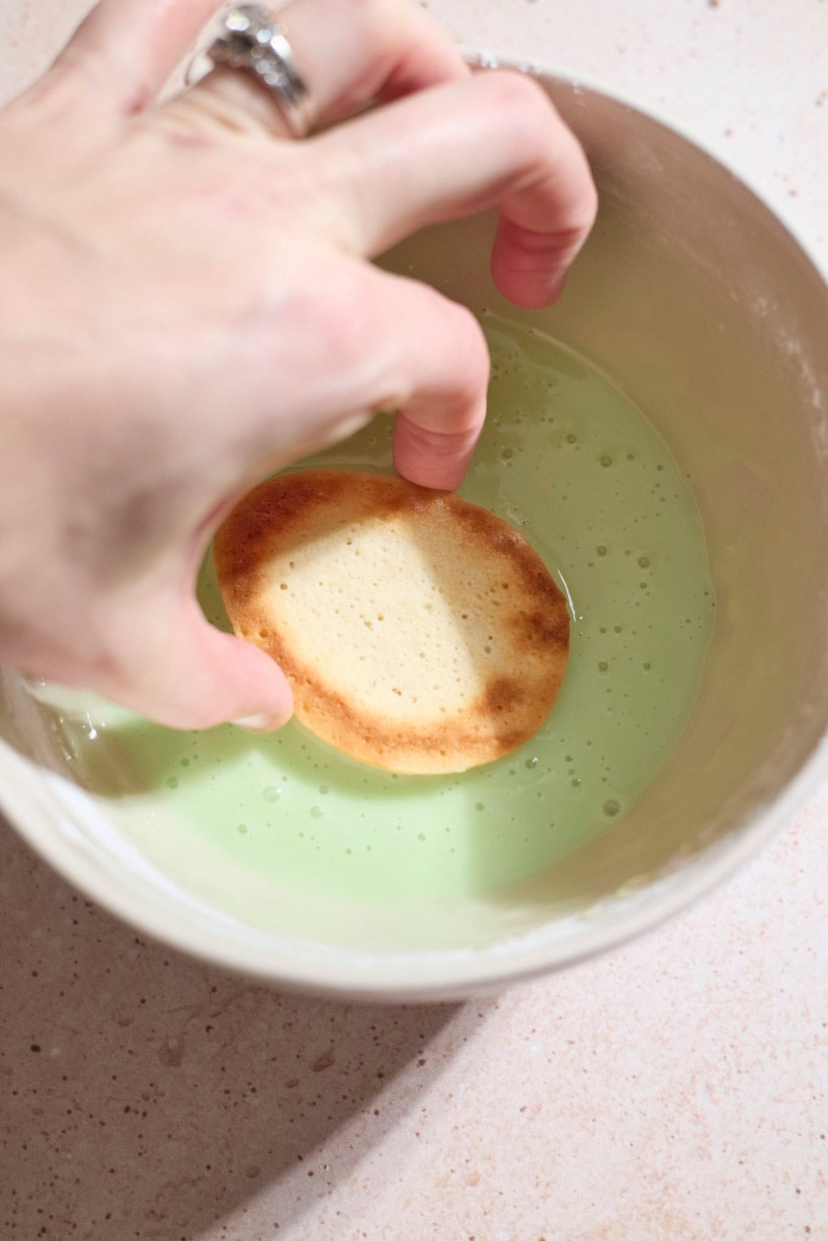 A cookie being dipped in the icing.
