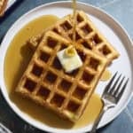 Sourdough Cornmeal Waffles with syrup being poured on top.