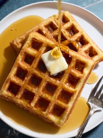 Sourdough Cornmeal Waffles with syrup being poured on top.
