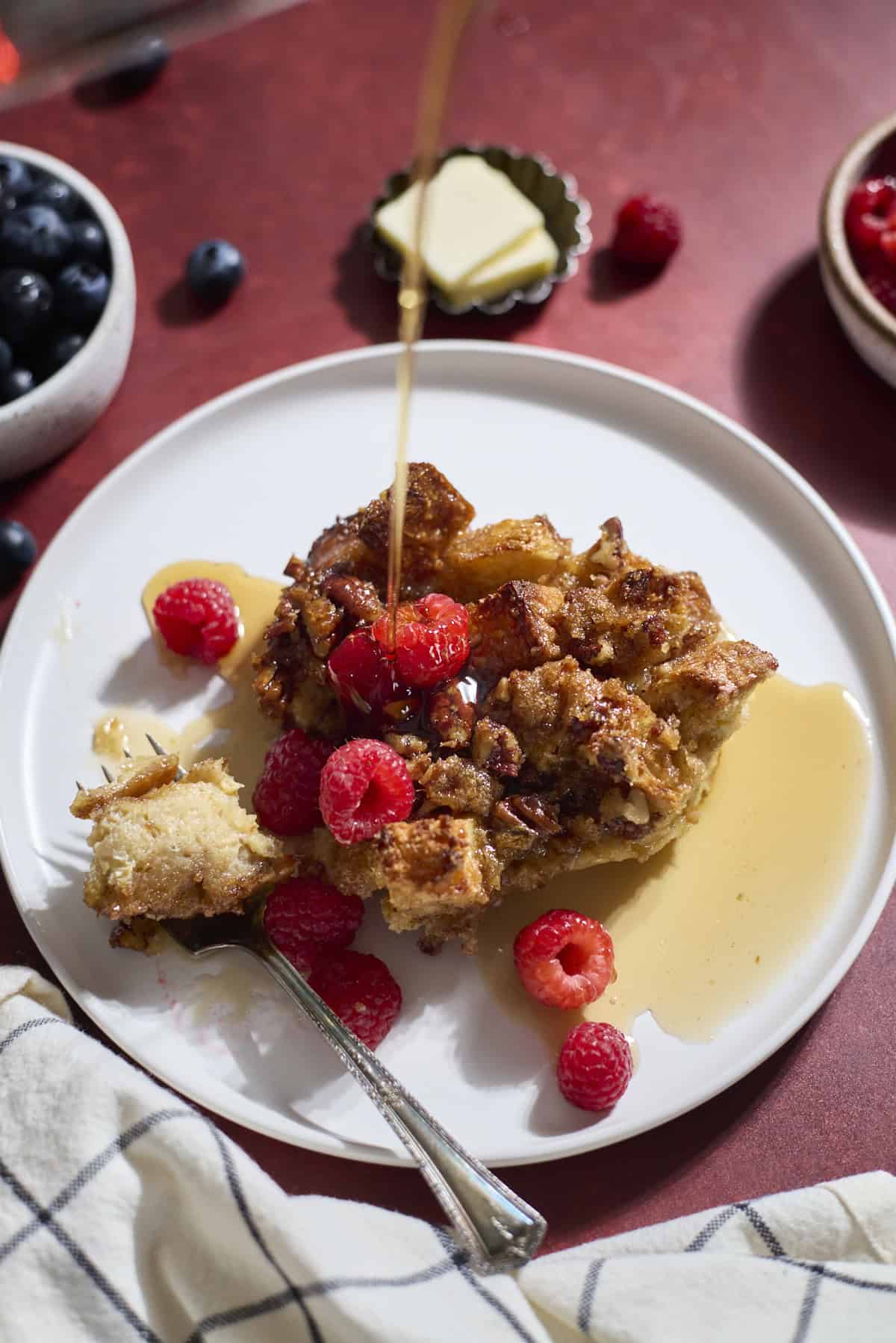 Sourdough French Toast Casserole on a white plate with syrup pouring on top.