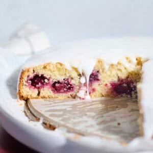 Sourdough Lemon Blackberry Cake with a drip of glaze falling down the side.