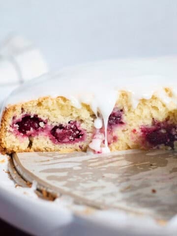Sourdough Lemon Blackberry Cake with a drip of glaze falling down the side.
