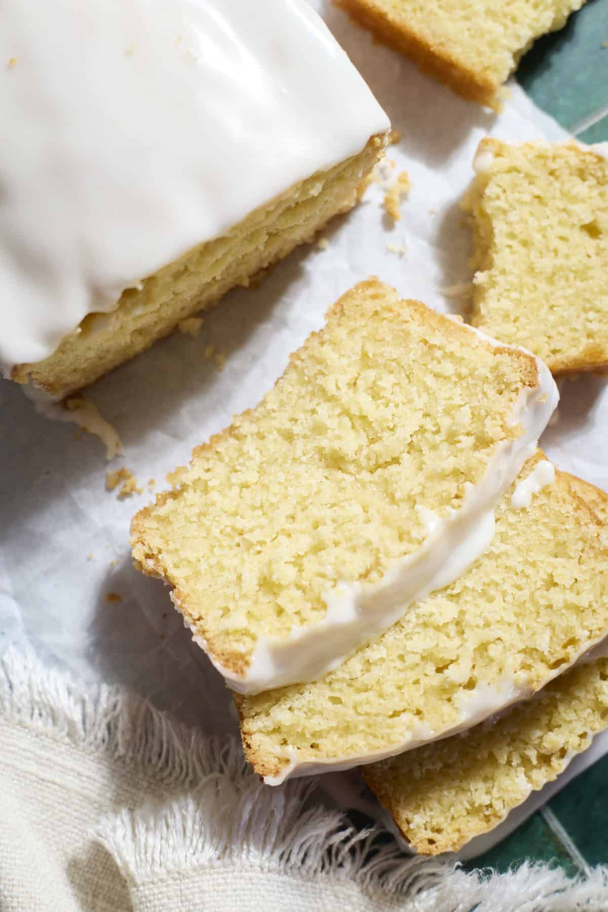 Slices of Sourdough Lemon Loaf Cake on white parchment paper.