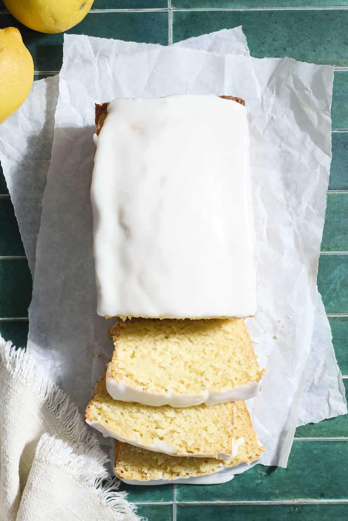 A sliced lemon loaf cake on white parchment paper.