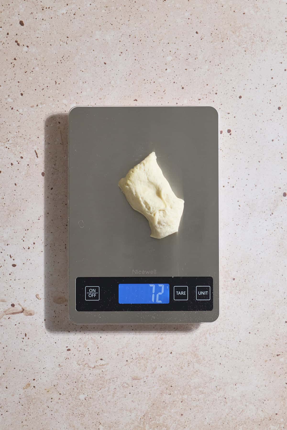 Dough being divided on a kitchen scale.