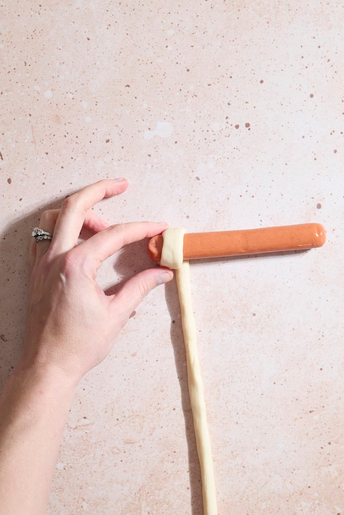 Dough at the start of wrapping around the hot dog.