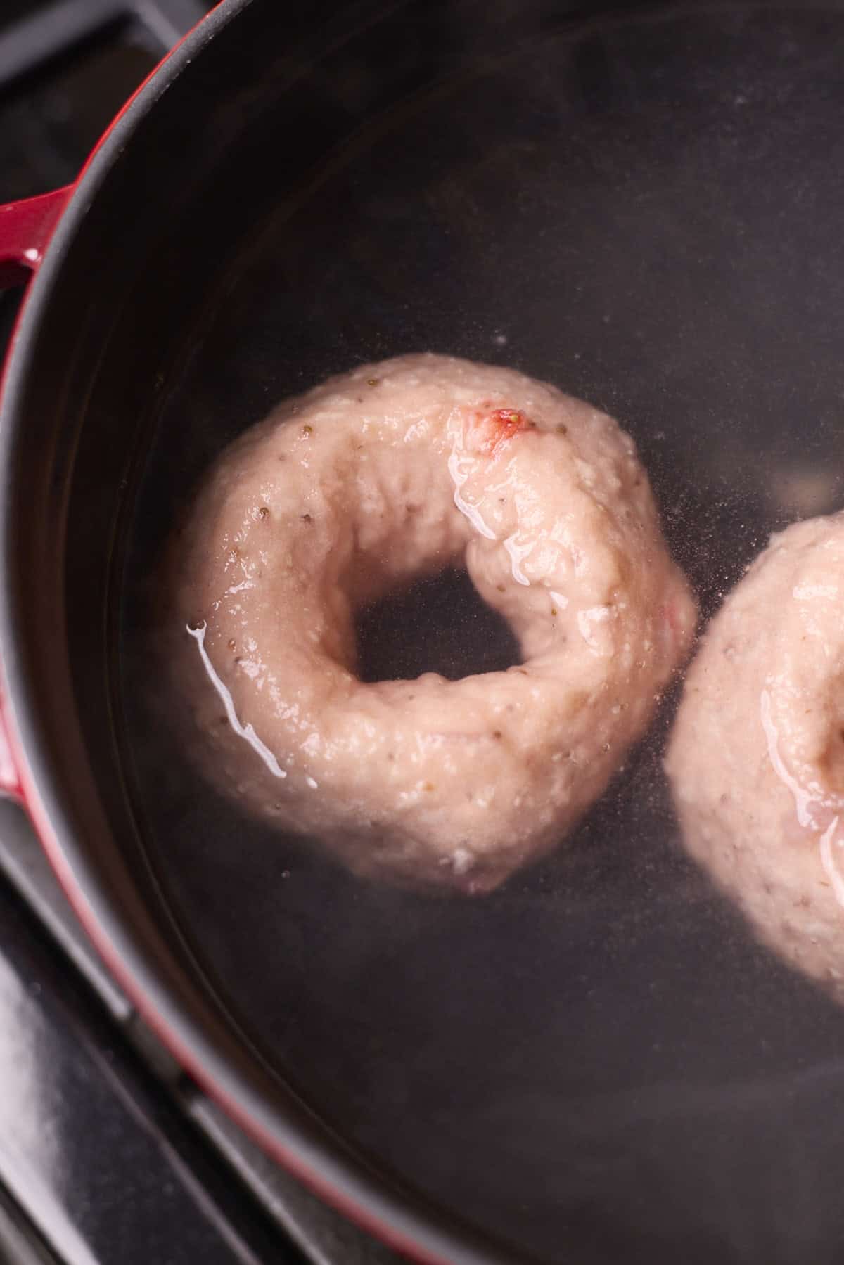Bagels boiling in a pot of water.