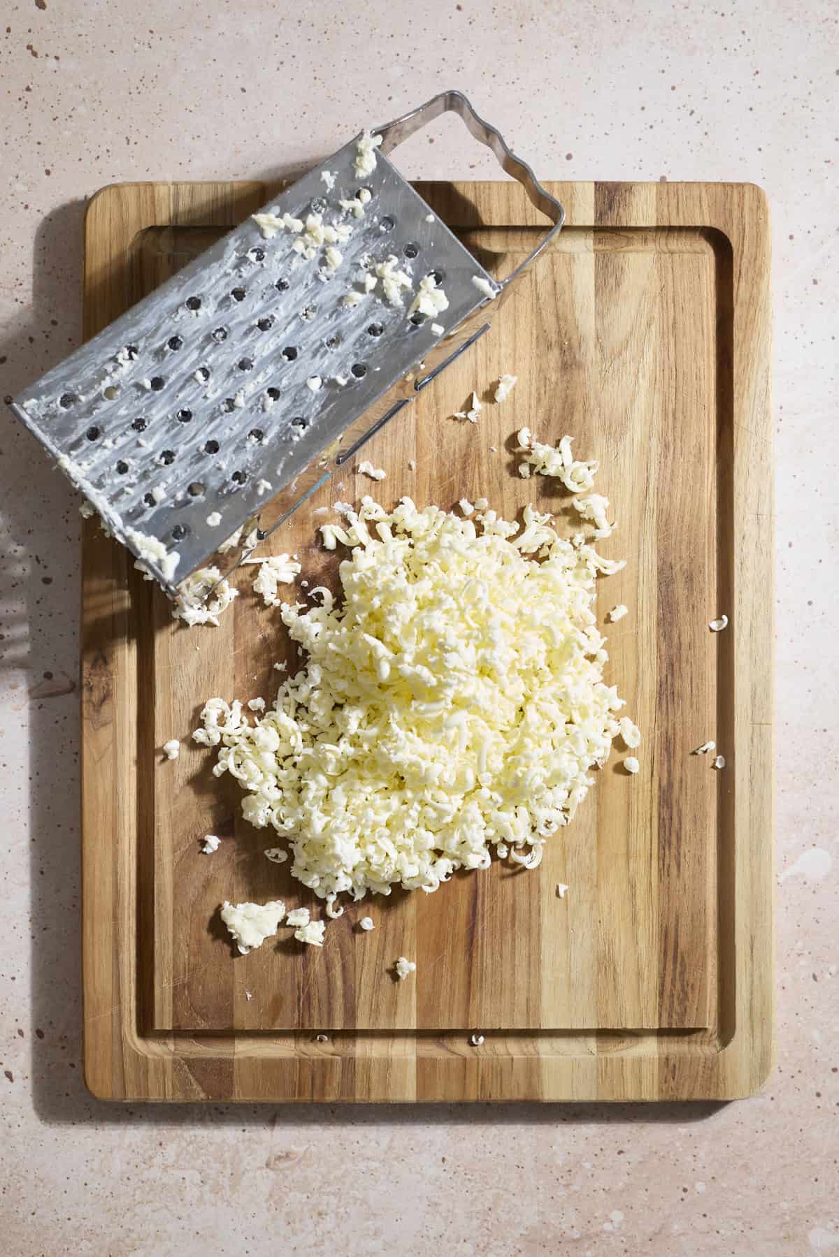 Grated butter on a wooden cutting board.