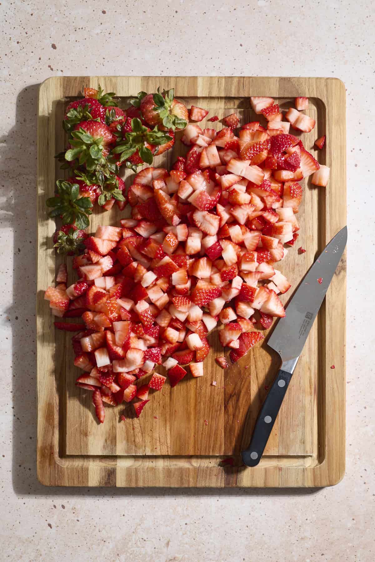 Diced strawberries on a wooden cutting board.