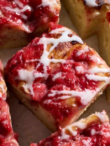 Slices of Sourdough Strawberry Donut Focaccia with icing drizzled on top.