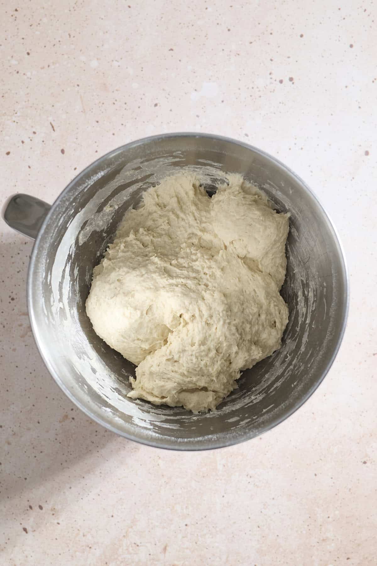Shaggy dough mixed together in the bowl of a stand mixer.