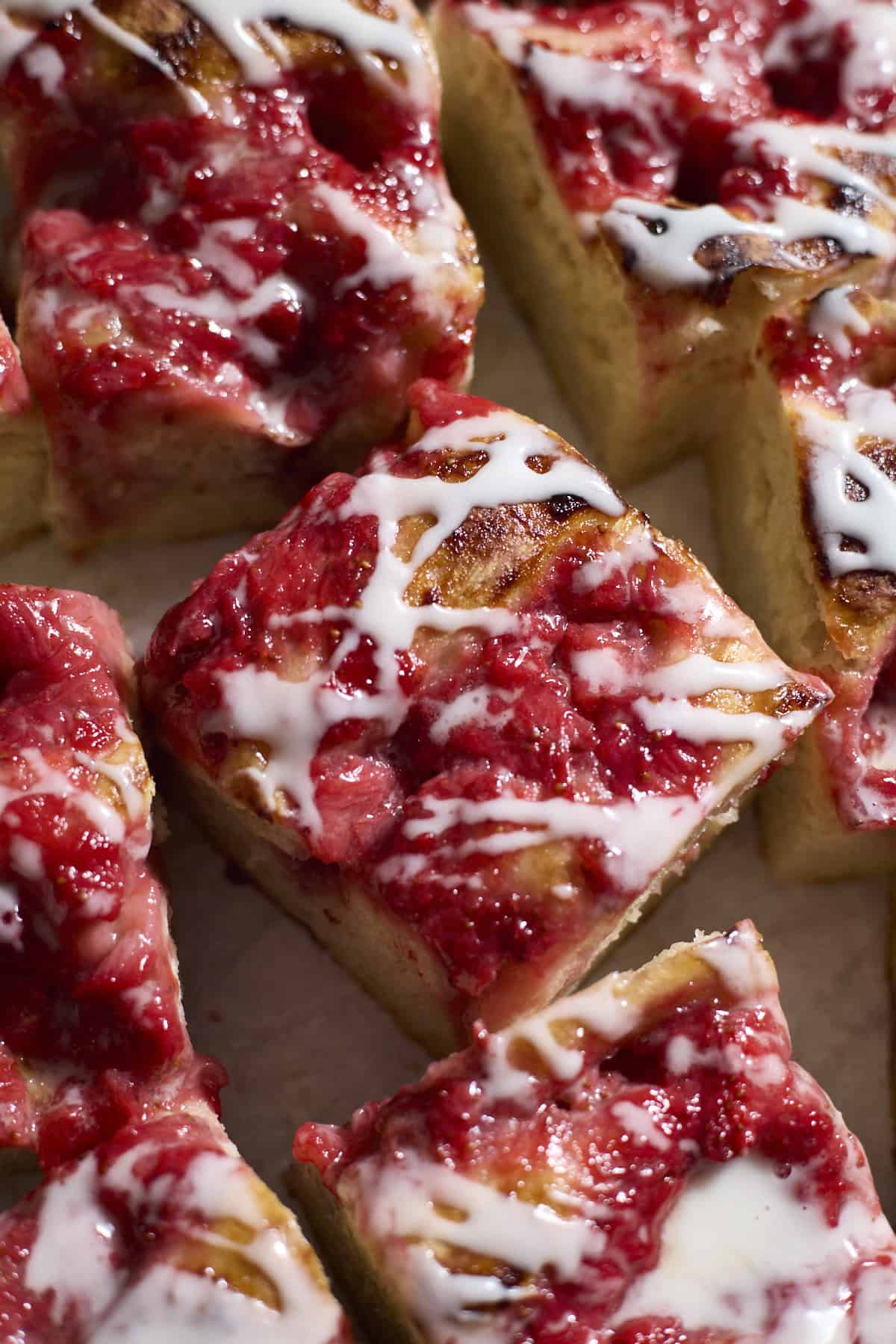 Slices of Sourdough Strawberry Donut Focaccia with icing drizzled on top.