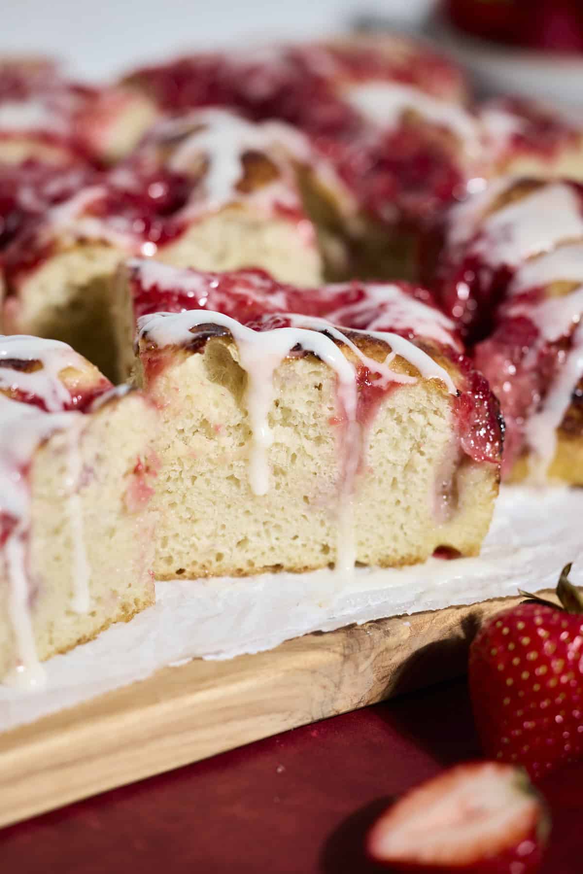 Slice of Sourdough Strawberry Donut Focaccia with icing dripping down.