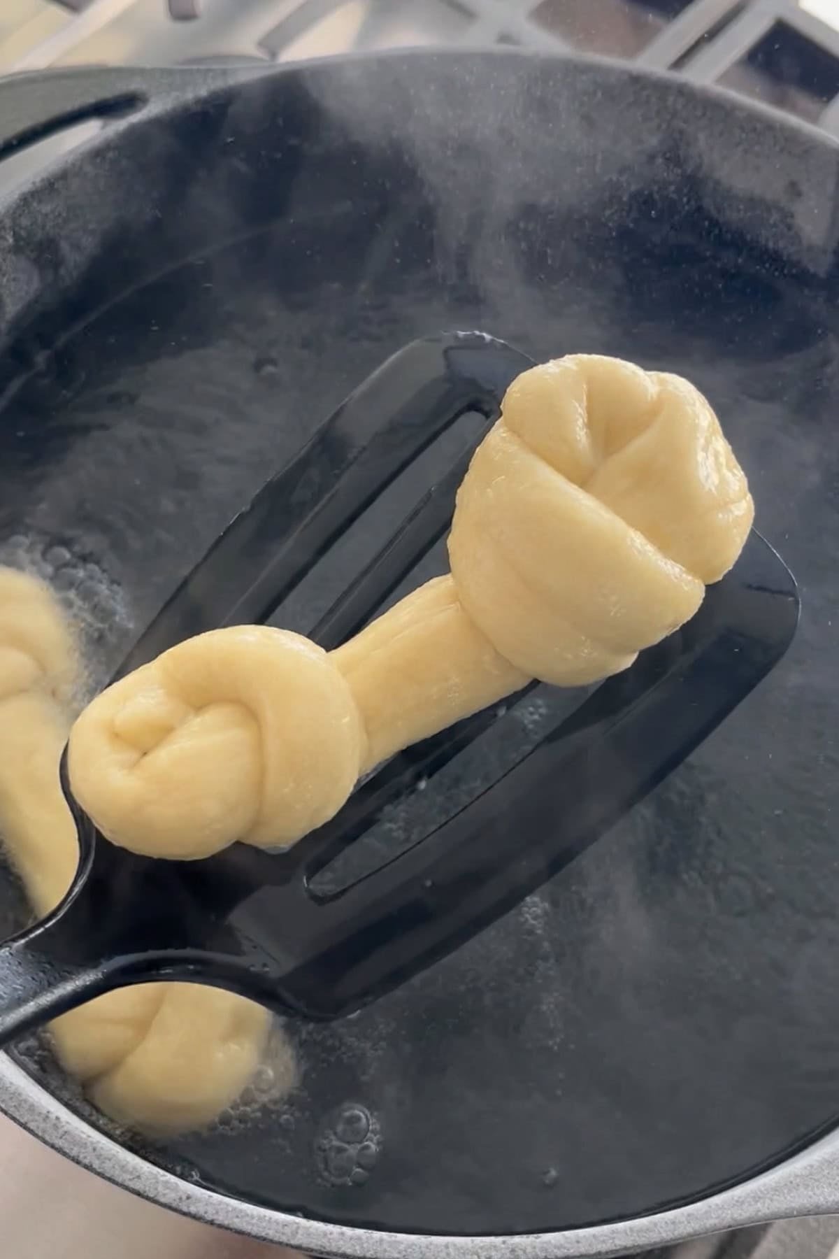 A pretzel bone being removed from the boiling water.