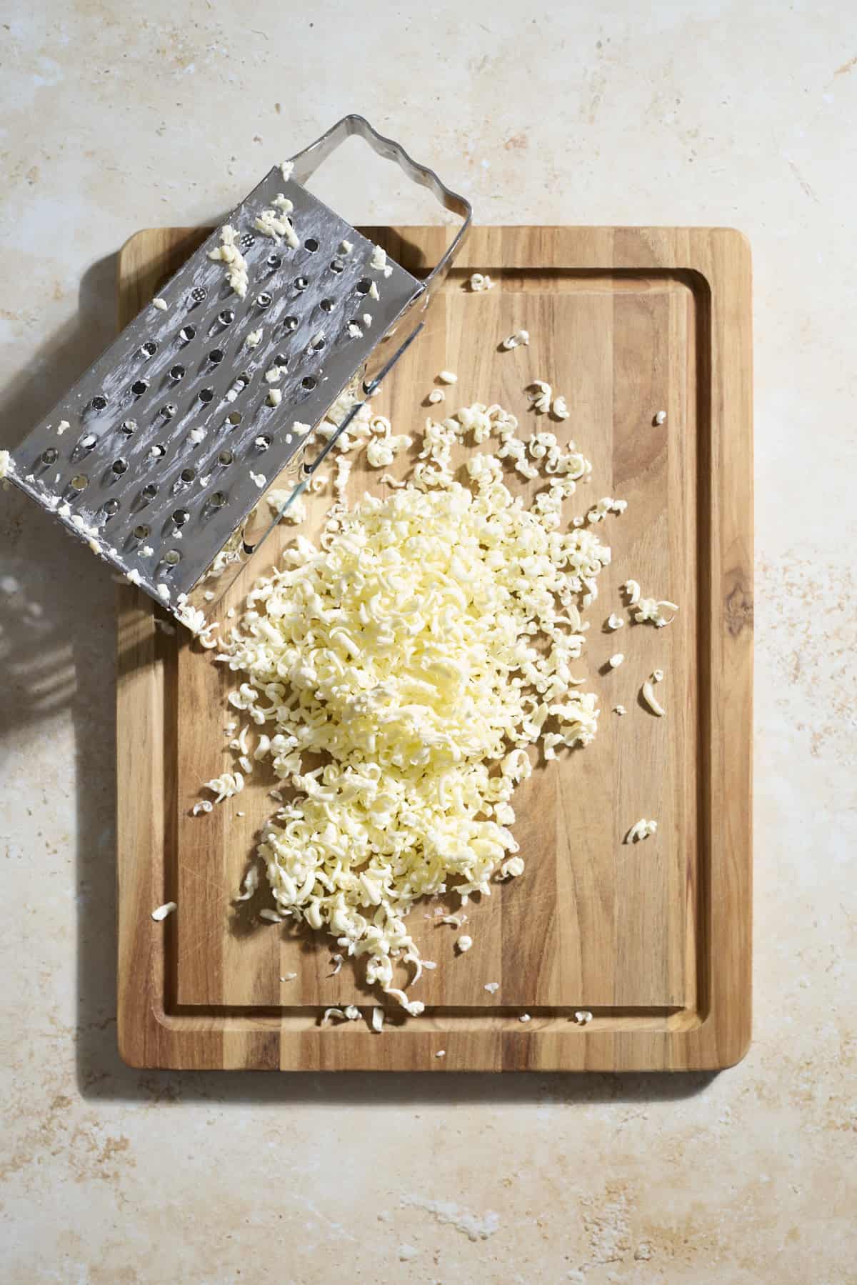 Grated butter on a wooden cutting board.