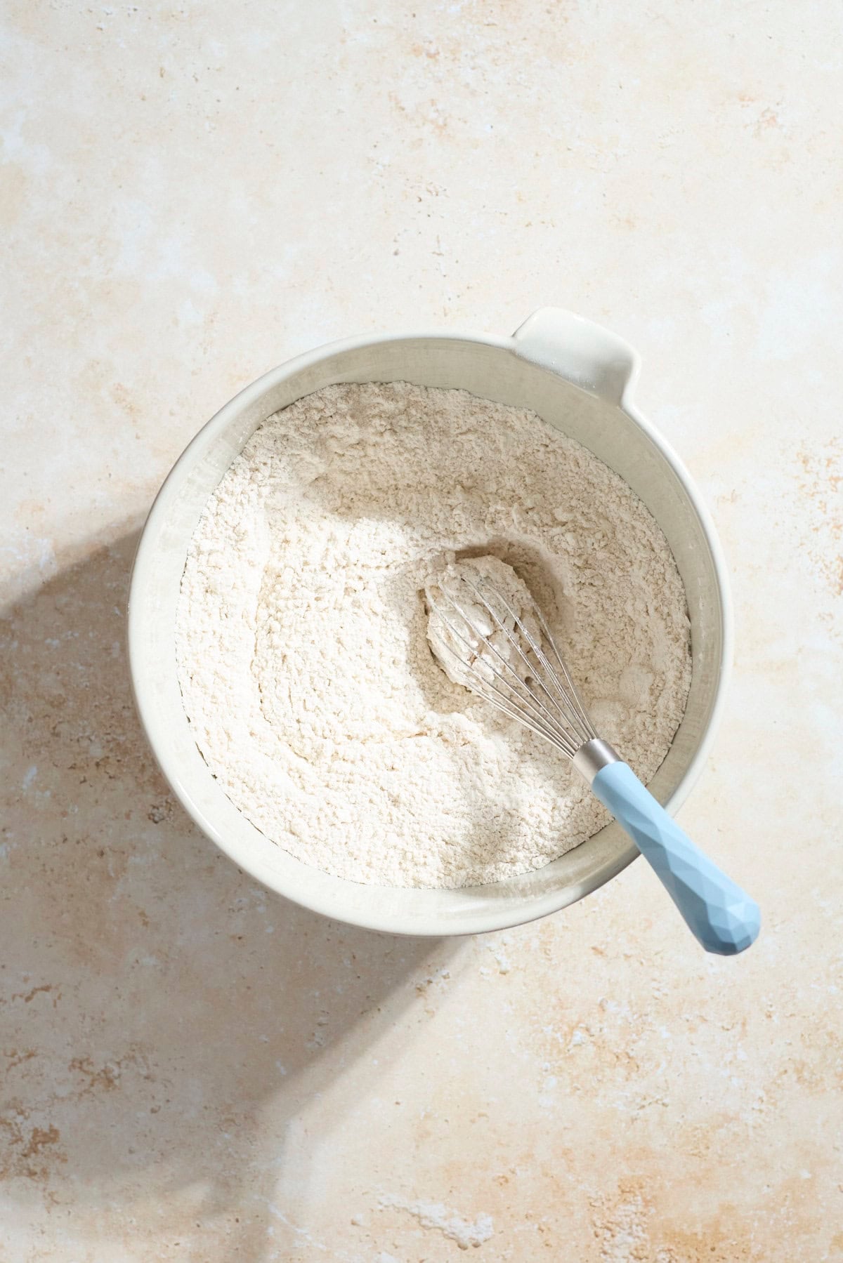 Dry ingredients in a mixing bowl with a whisk.