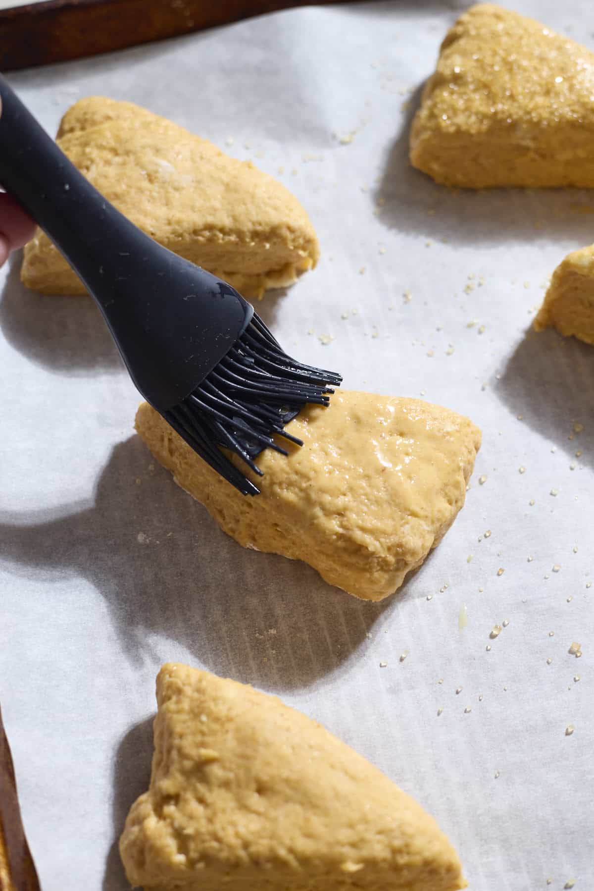Egg wash being brushed onto scones.